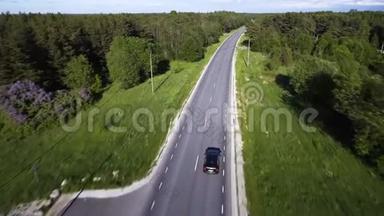 两车道<strong>森林</strong>公路的鸟瞰图，一辆黑色汽车在两边<strong>茂密森林</strong>中的绿树之间行驶。